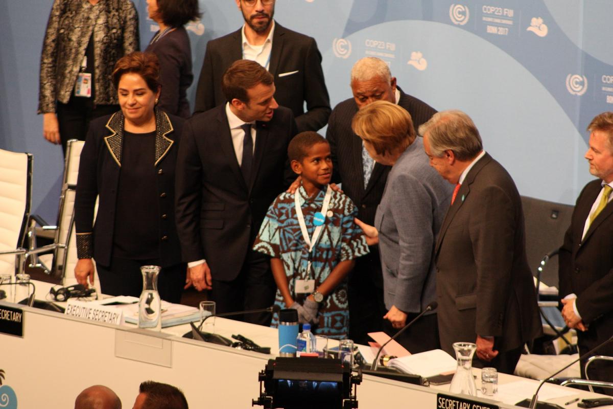 German Chancellor Angela Merkel and French President Emmanuel Macron talk to Timoci Naulusala, the Fijian boy who addressed delegates at the opening of the COP23 high-level segment. Source - CLEW 2017.