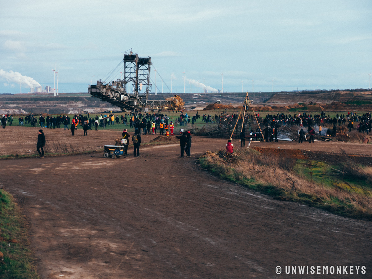 Photo shows protesters and coal mine with excavation machine at Lützerath, Germany. Photo: Lützi lebt/Unwisemonkeys. 