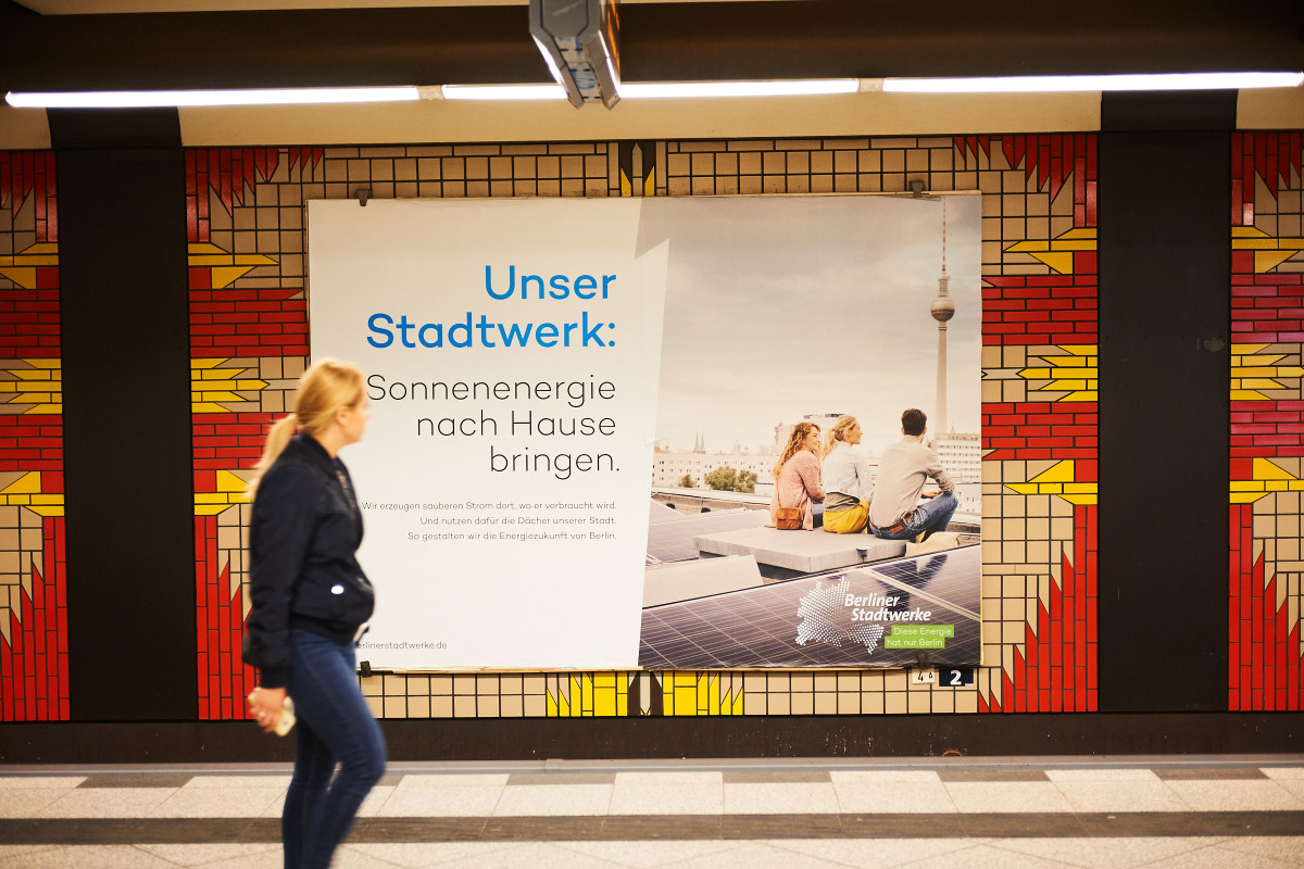 Photo shows a billboard advertising local power production by Berliner Stadtwerke in a Berlin subway station. Photo: Darius Ramazani.