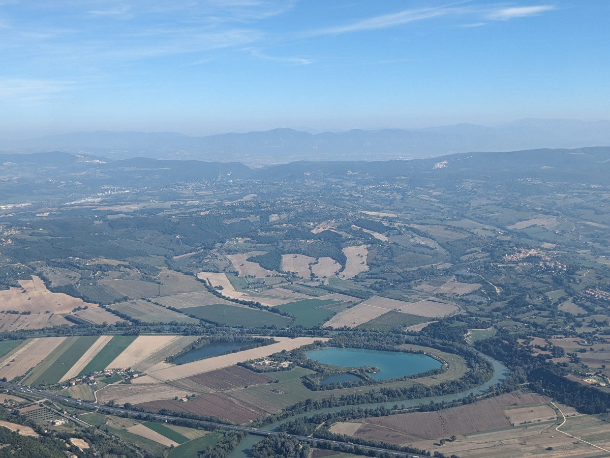 Photo shows aerial view of Italy on the border of Lazio and Umbria, with lake, river Tiber and fields, and mountains in the background. Photo: CLEW/Wettengel.