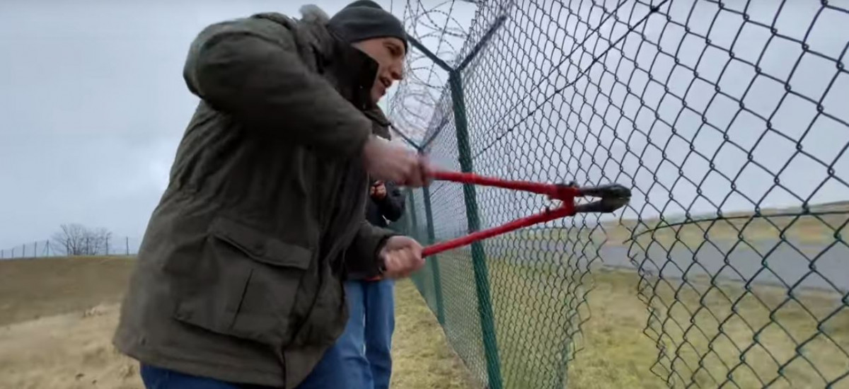 A "Last Generation" activists cuts a fence to enter the airfield of Munich airport. Still from Youtube.